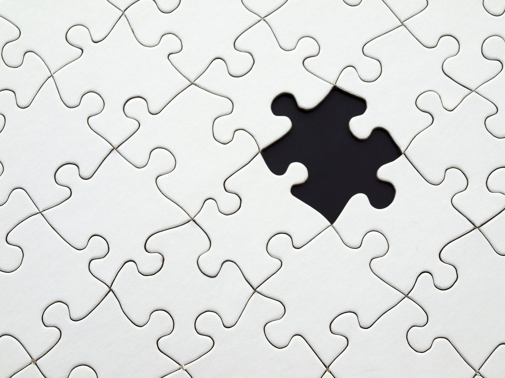 A clean, white jigsaw puzzle with a single missing piece, symbolizing the 'Information Gap' that prevents youth from completing the journey to economic inclusion.